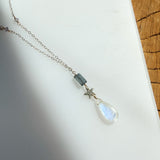 Necklace with a teardrop-shaped pendant and silver star on a white surface