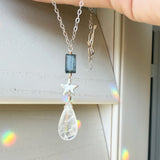 Necklace with a moonstone teardrop pendant, star-shaped charm, and kyanite against a neutral background.